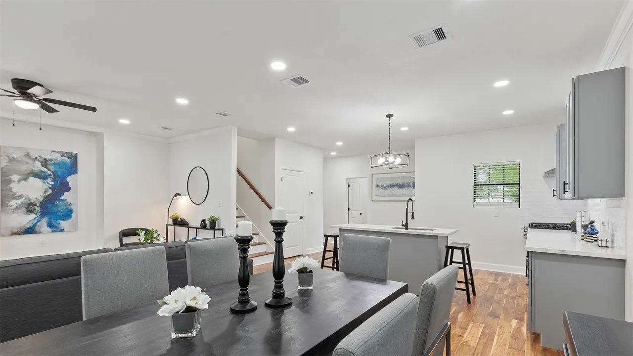 Dining toward kitchen and stairwell, with linear chandelier above the kitchen island