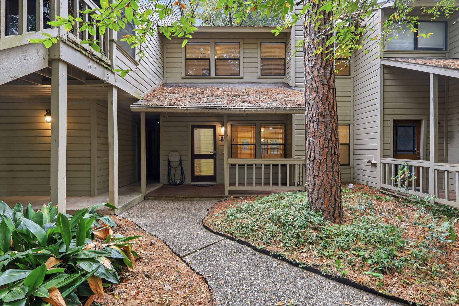 Front exterior of 28 Sawmill Grove Ln, a two-story townhome under tall pines in Grogan's Mill, The Woodlands