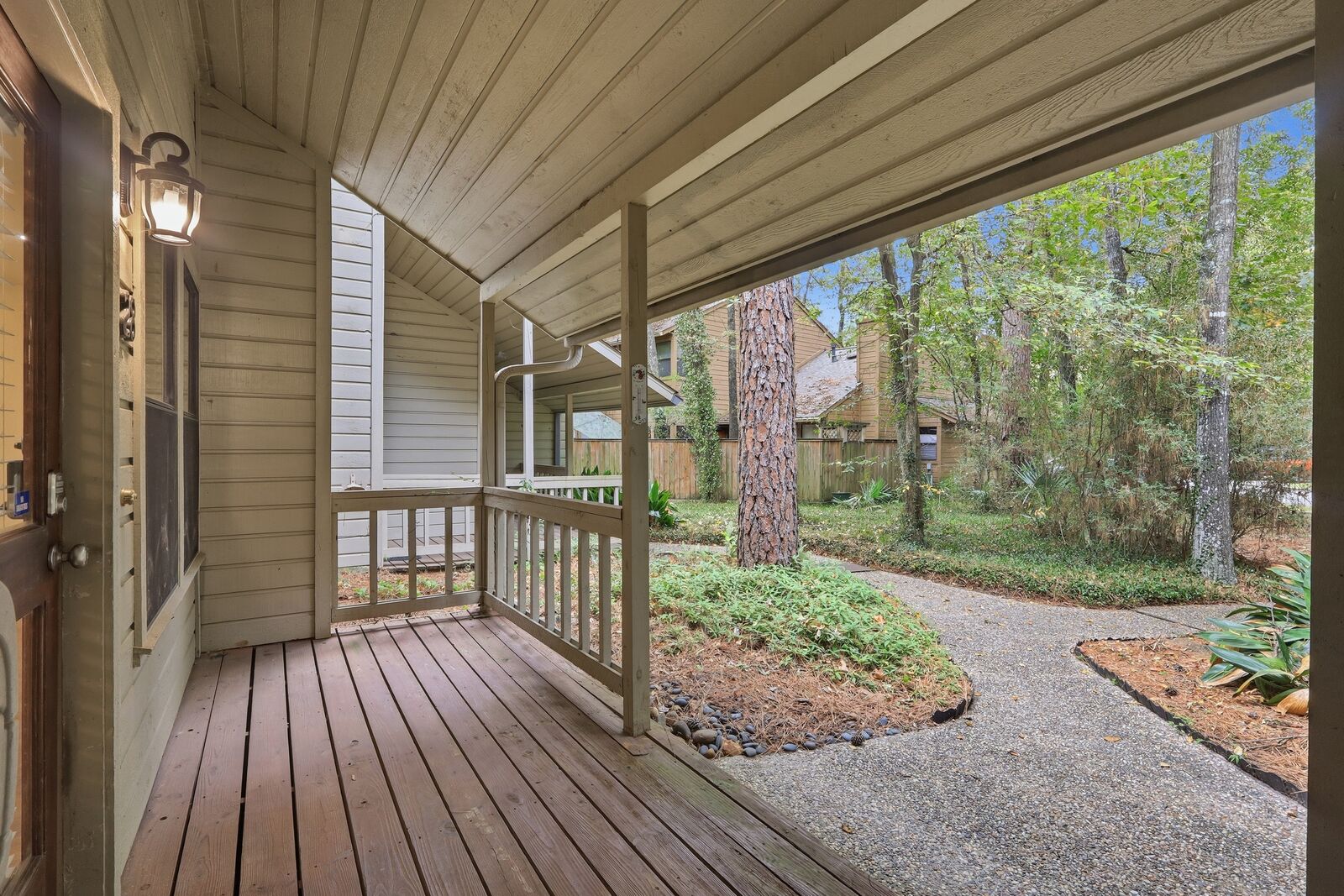 Covered front porch with wood decking and wooded courtyard view