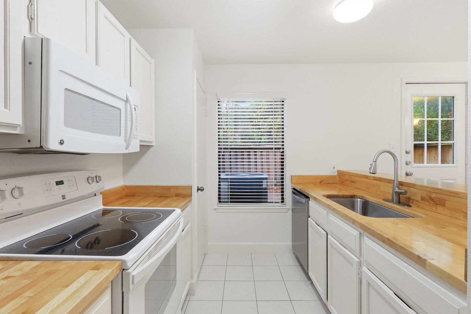 Kitchen with butcher-block counters, electric range, built-in microwave and dishwasher