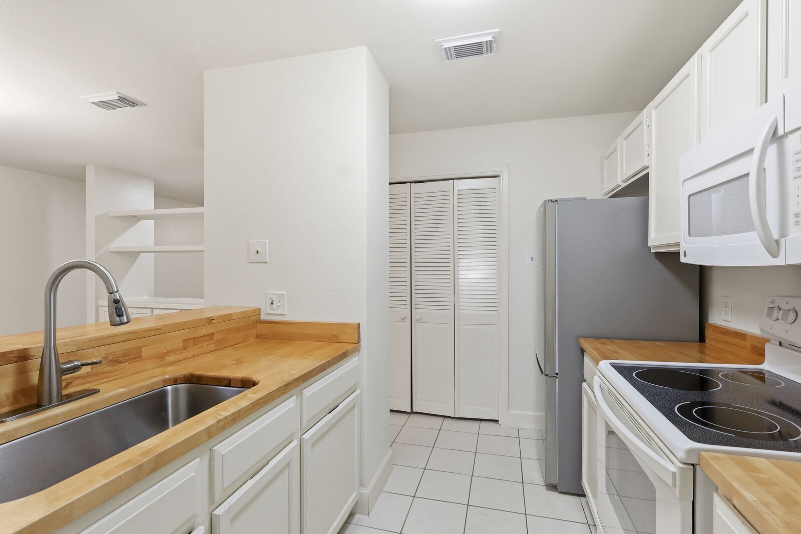 Kitchen with butcher-block counters, stainless refrigerator and pantry