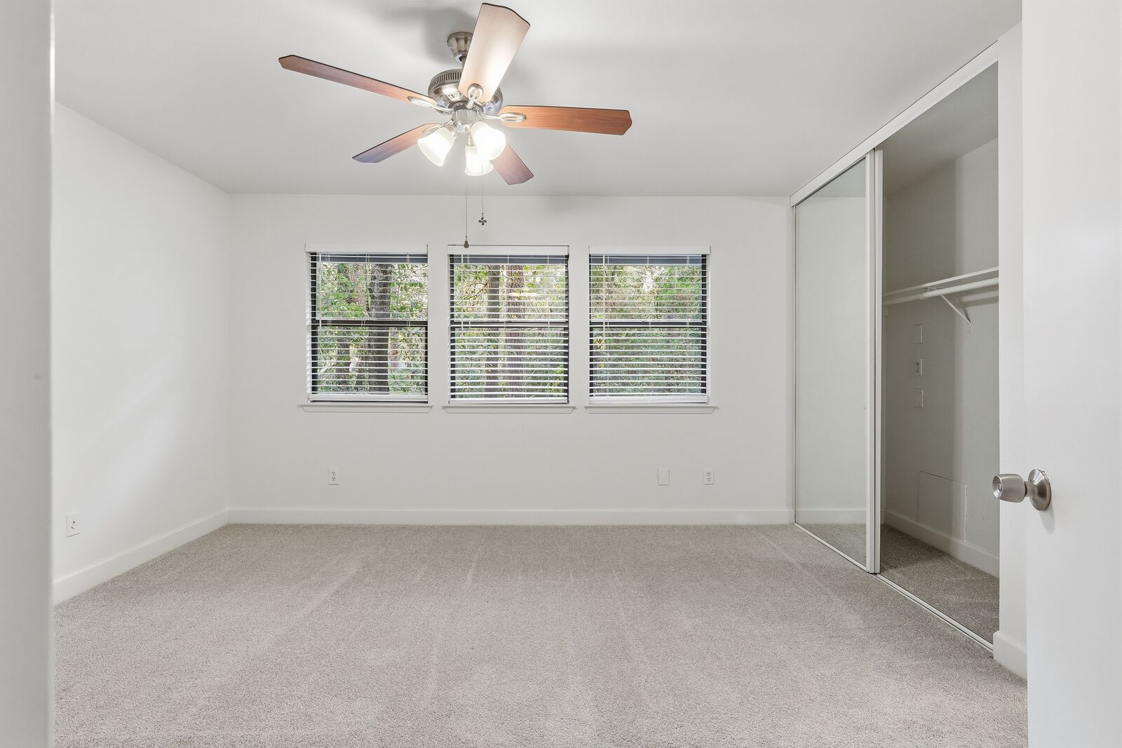 Primary bedroom with ceiling fan and triple windows