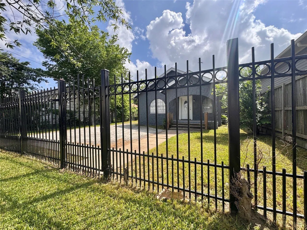 Front view from the street through the black iron security gate enclosing the property