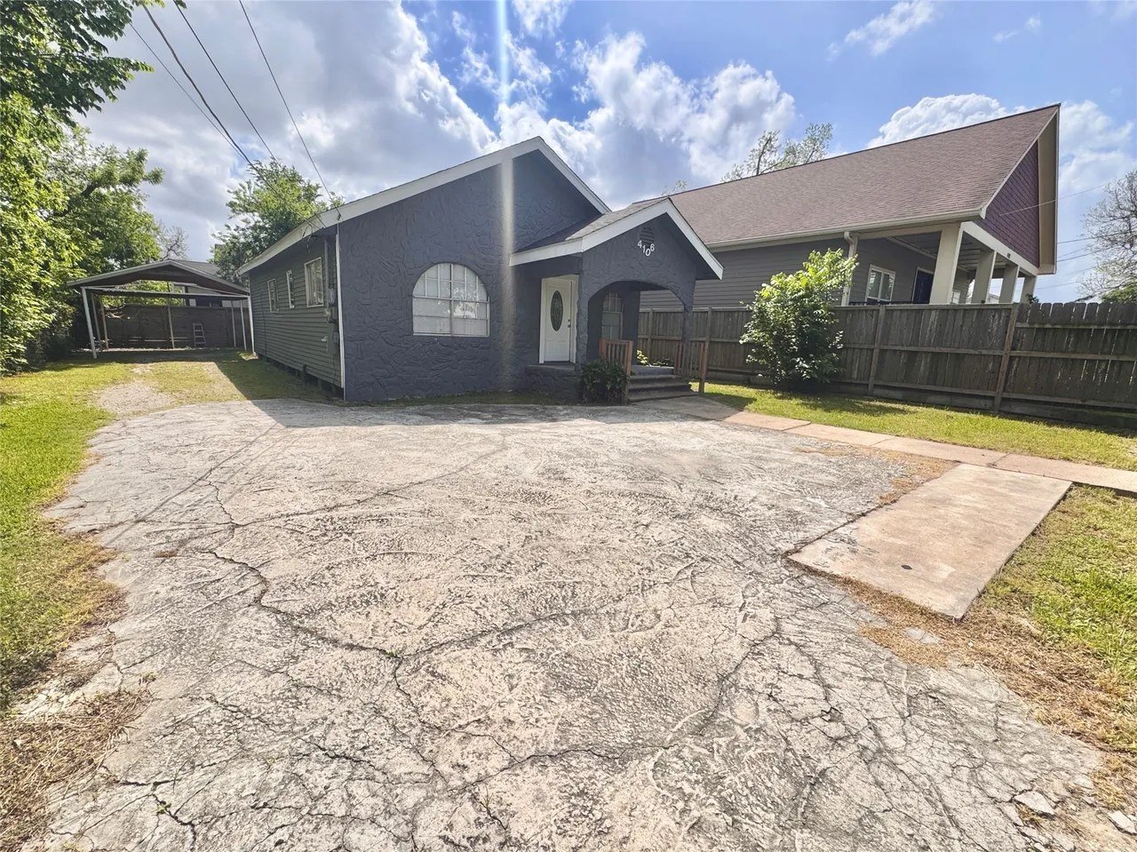 Side / driveway view showing the long concrete driveway and detached carport