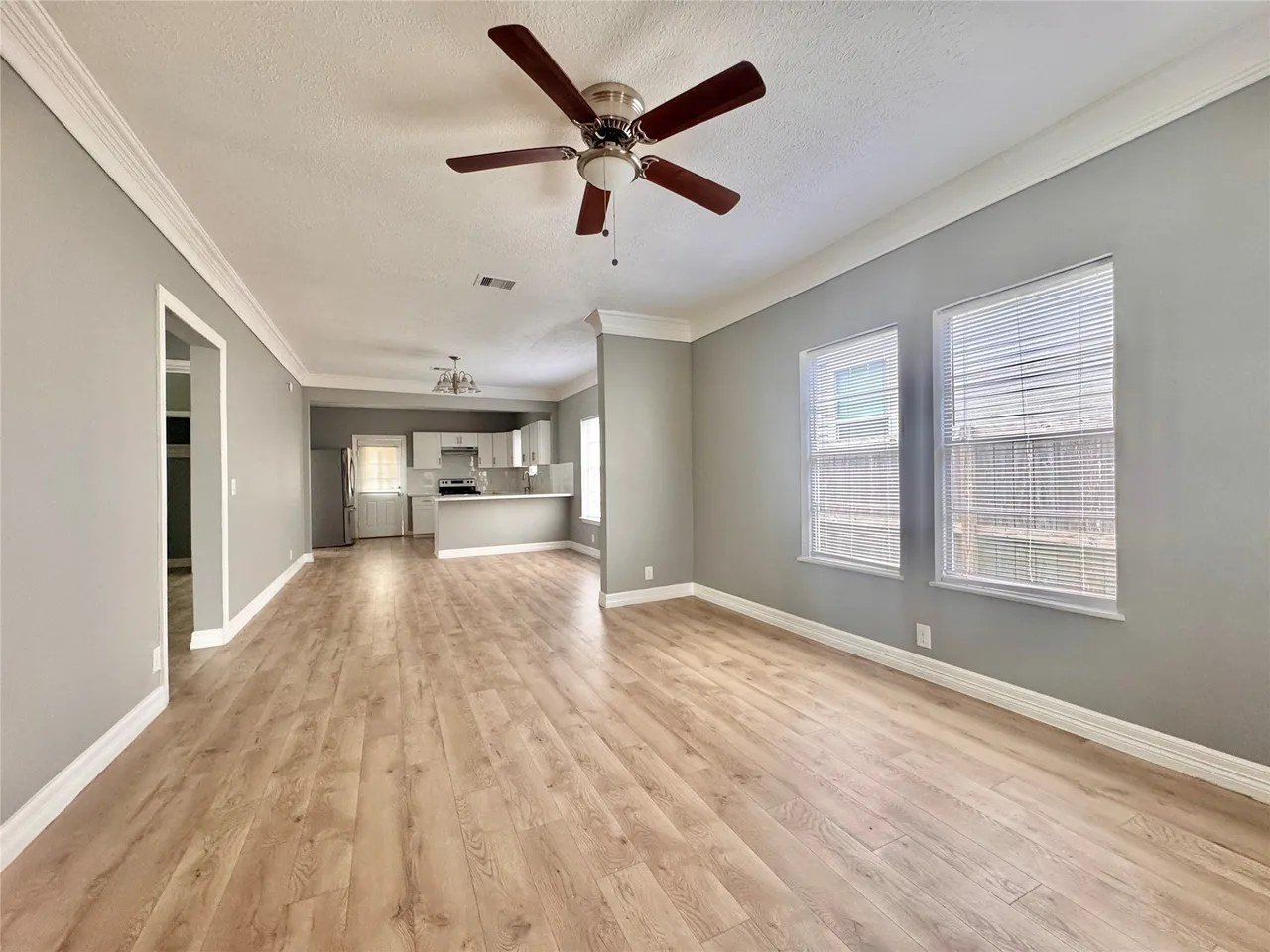 Family room with ceiling fan, large windows, and laminate flooring