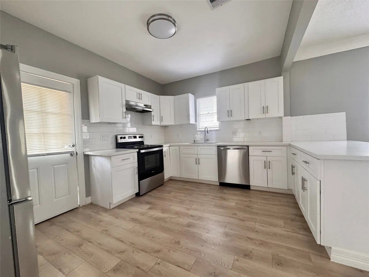 Kitchen with white shaker cabinets, quartz counters, subway-tile backsplash, and stainless appliances