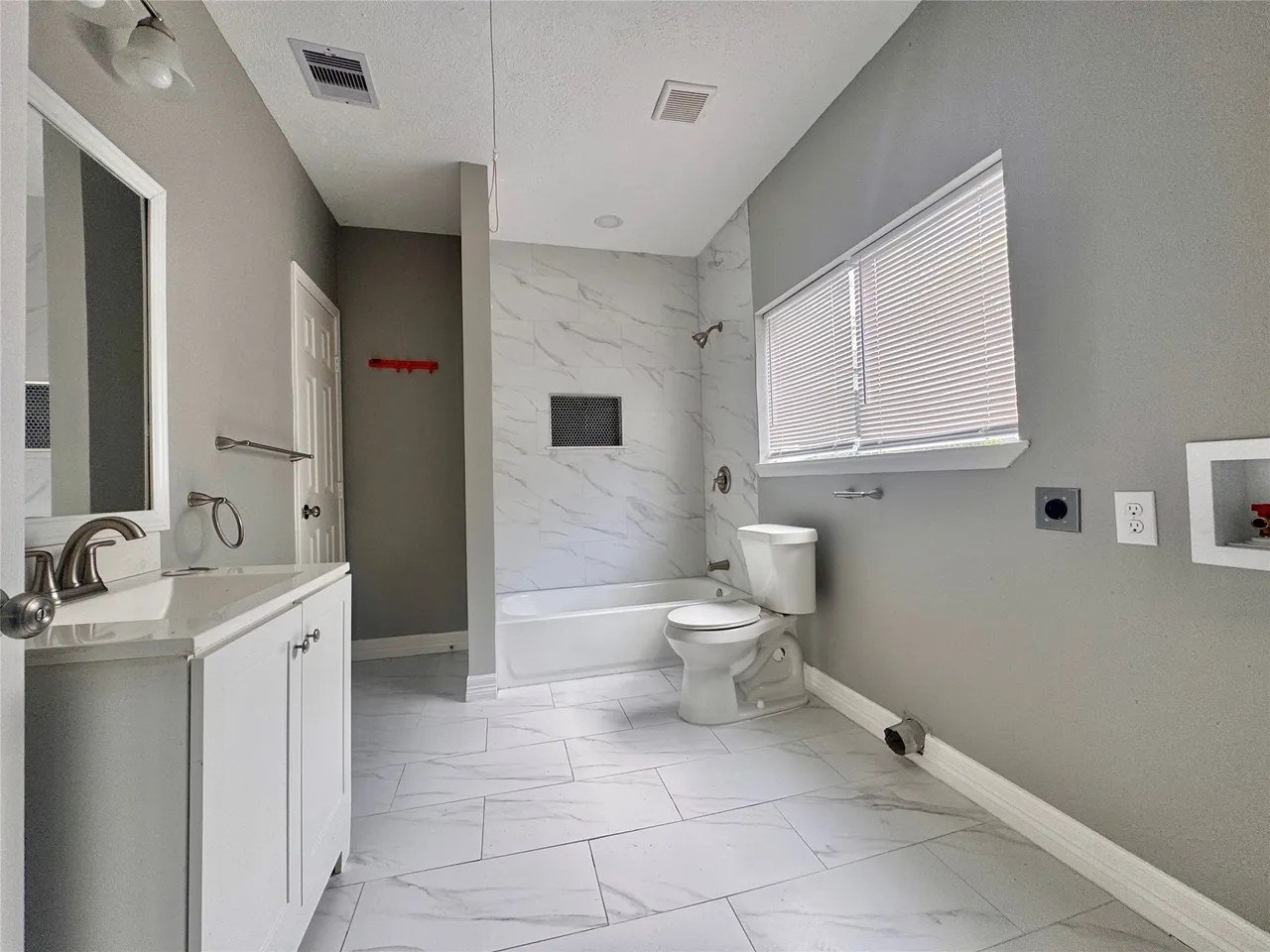 Full bathroom with vanity, marble-look tub surround, and washer/dryer hookups