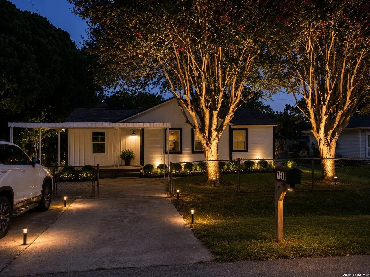 Front of the home at twilight with lit walkway and mature crepe myrtle trees