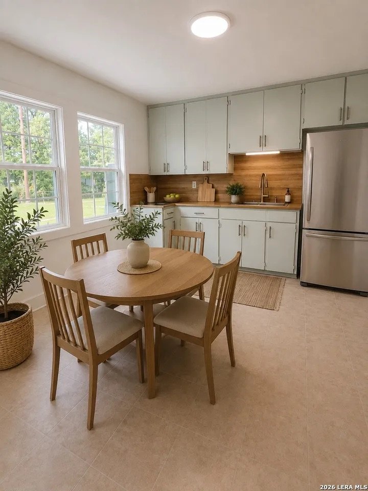 Updated eat-in kitchen with sage-green cabinets, butcher-block counters, and stainless refrigerator