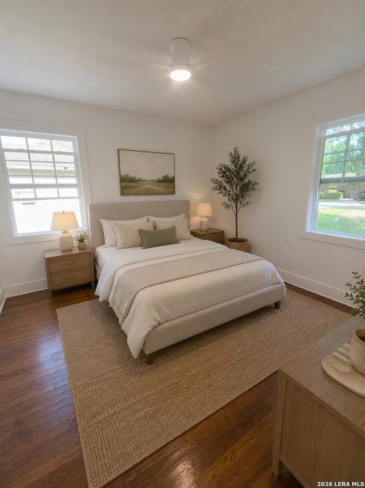 Bedroom with wood floors, two windows, and ceiling fan