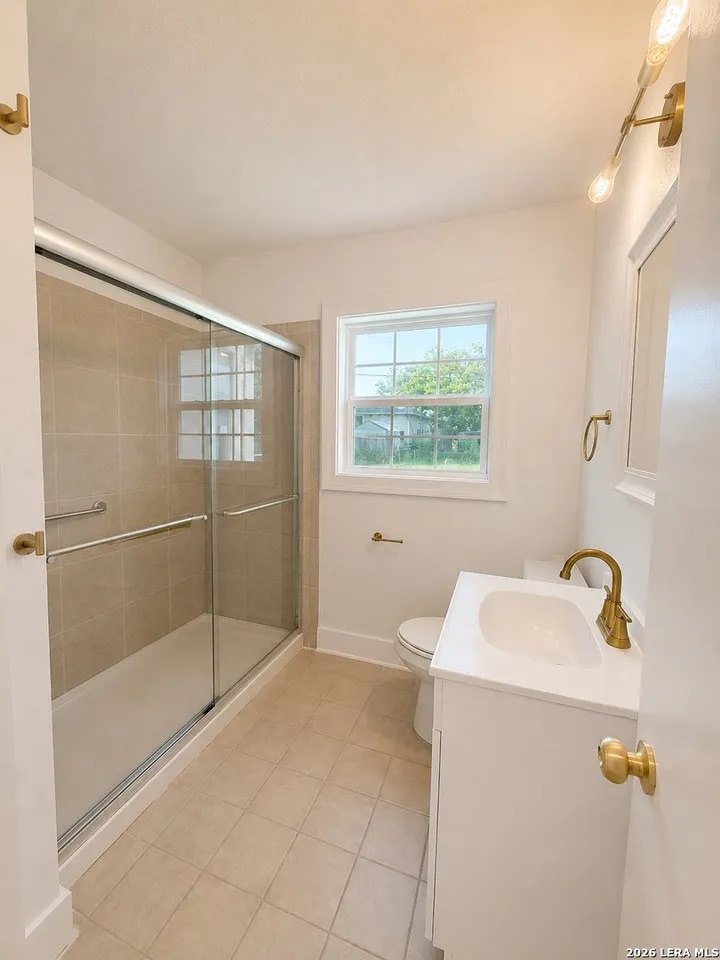 Updated bathroom with glass-door shower and brass fixtures