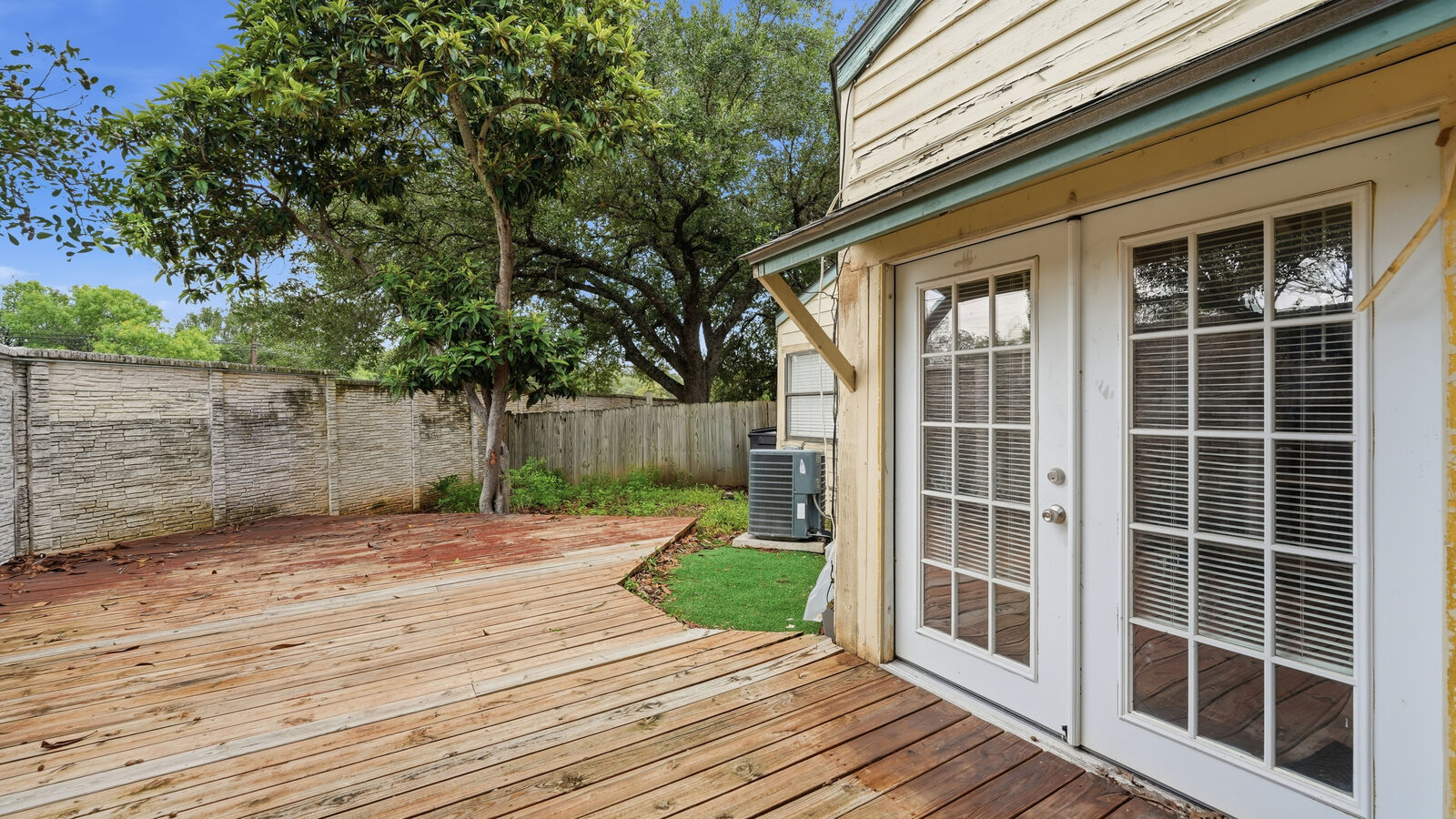 Backyard fence line, HVAC unit, and mature tree