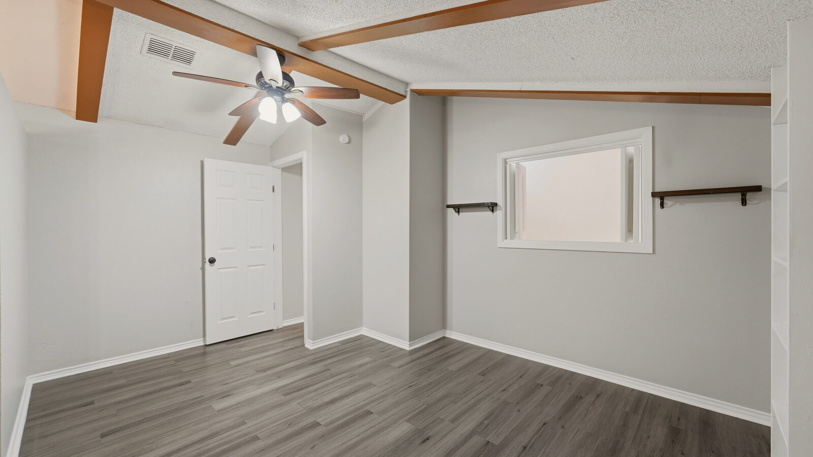 Primary bathroom with double vessel sinks, gold-framed mirrors, and swirl-pattern accent wall under a vaulted wood-beam ceiling