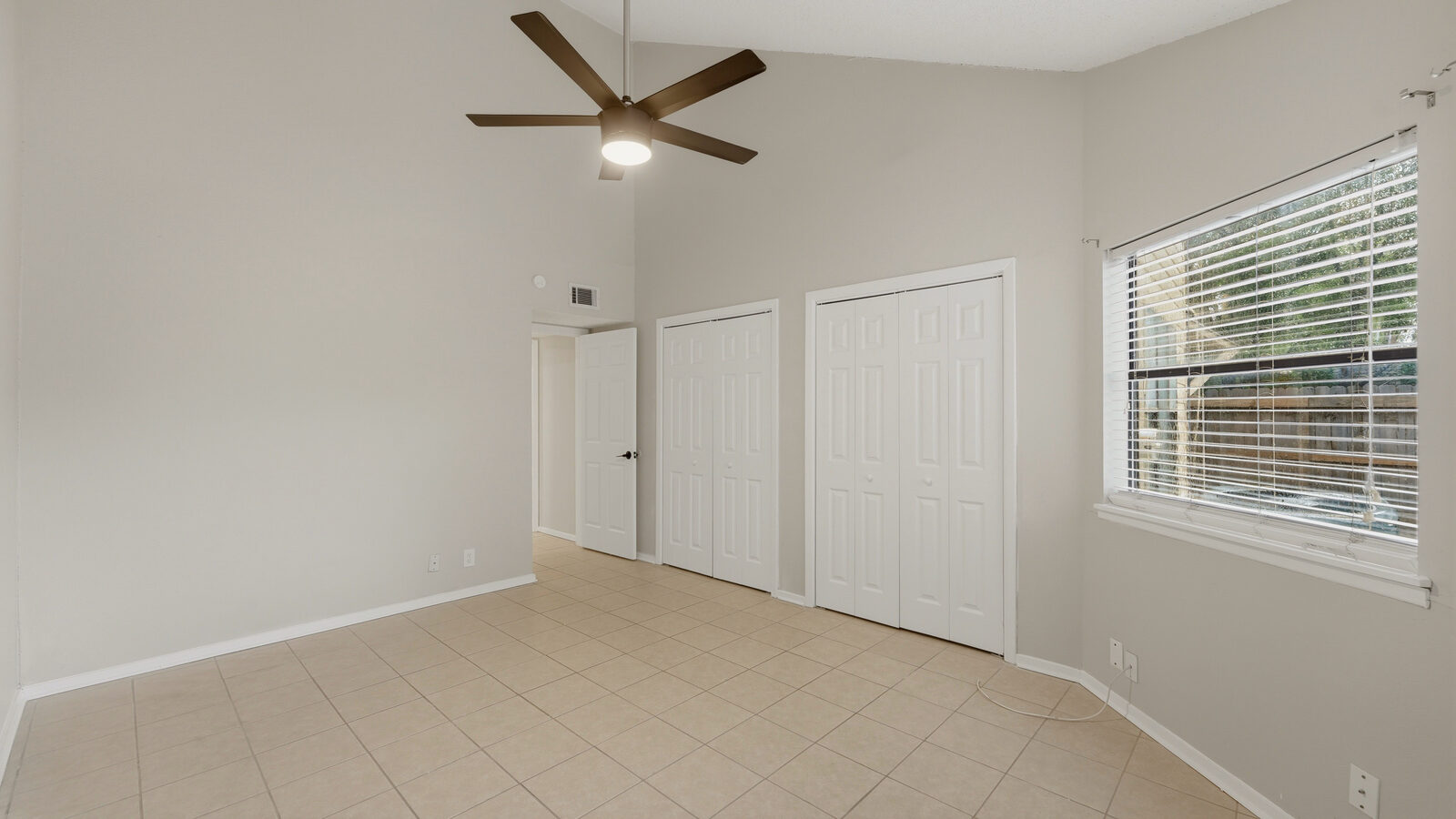 Primary bedroom with vaulted ceiling, built-in shelving nook, and ceiling fan