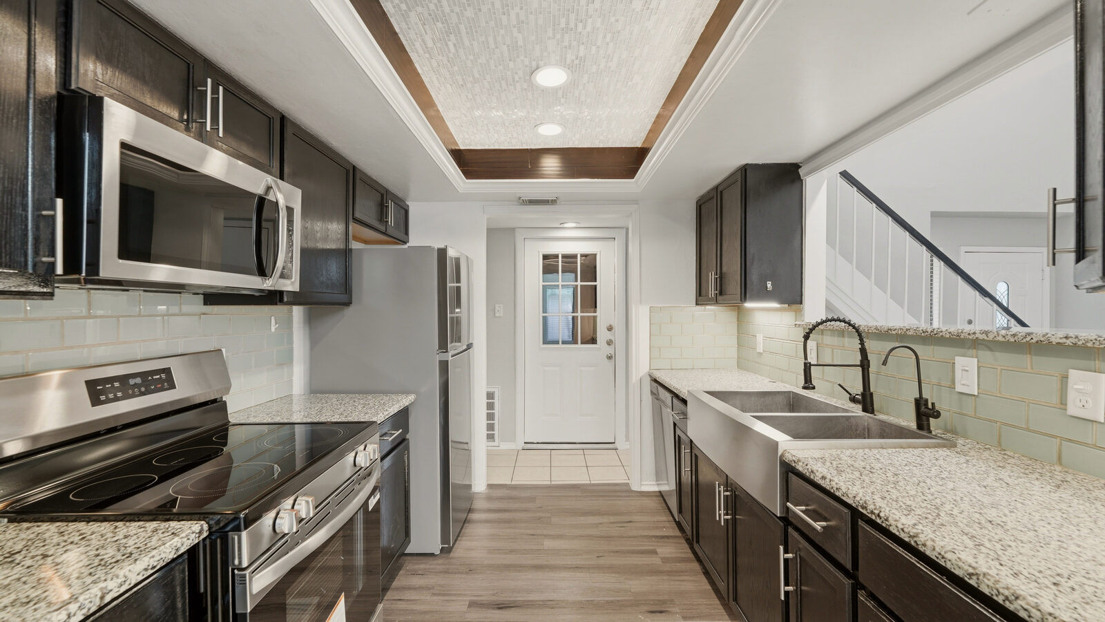 Kitchen with dark cabinets, granite counters, subway-tile backsplash, and stone accent wall